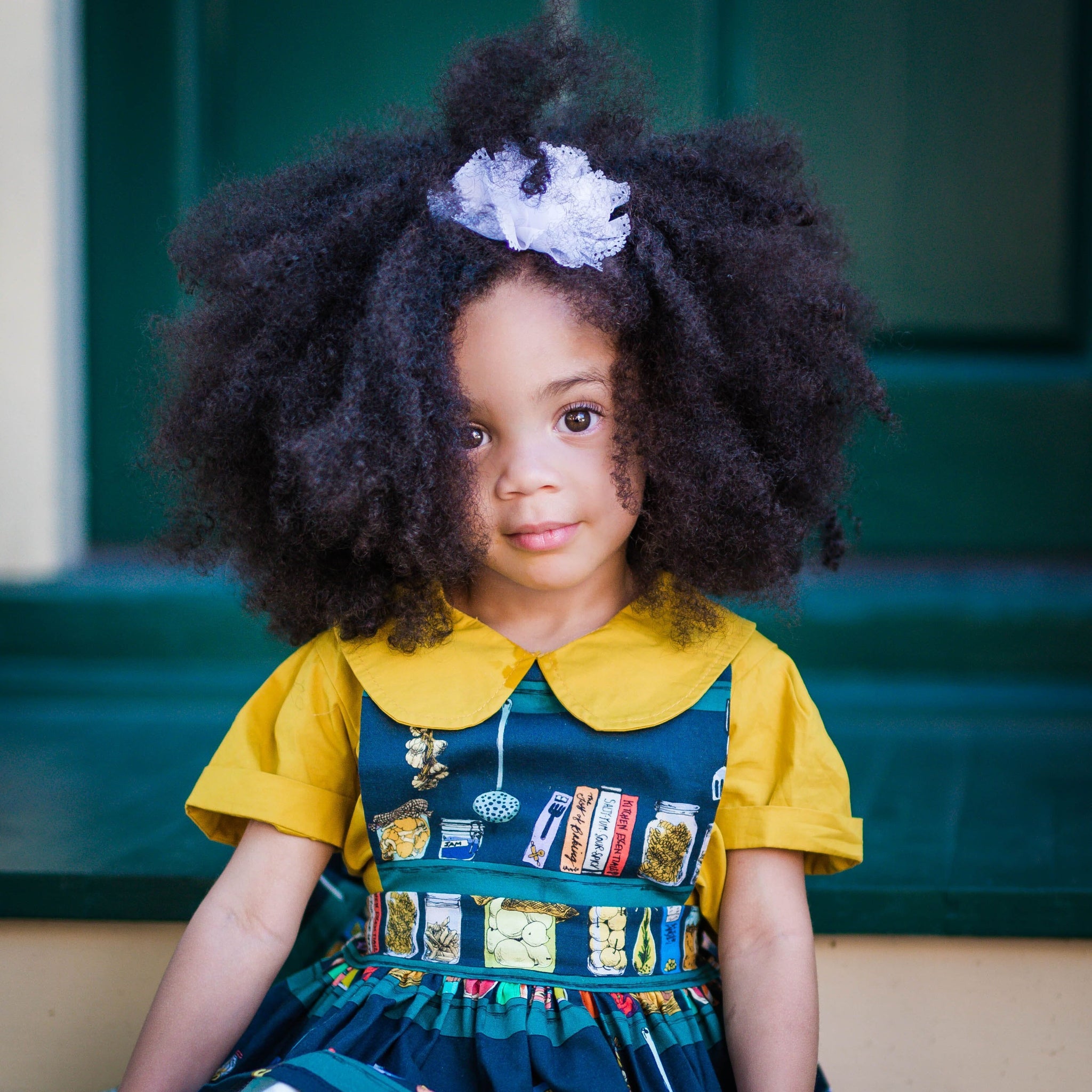 Toddler wearing girls pinafore dress in Canning print over mustard collared shirt.  Unique toddler clothing for your tiny style icon.